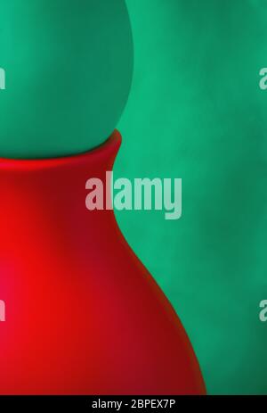 Abstract bicolor design - part of a red ceramic vase with an egg on a green background closeup. Stock Photo