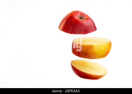 Sliced apple floating on white background. Fruit slice falling on bright backdrop. Stock Photo