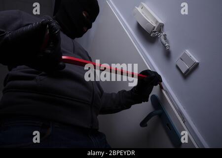 Thief Trying To Break The Door With Crowbar Stock Photo