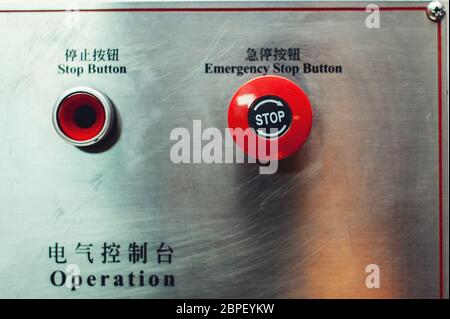 red emergency stop button, inscriptions in English and Chinese Stock Photo