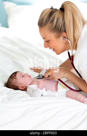 Pediatrician examines baby with stethoscope at home