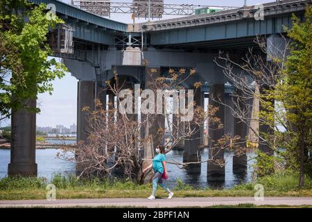 In Little Bay Park, a woman who appears to be pregnant walks in front of the entrances to the Throgs Neck Bridge. in Whitestone, Queens, New York. Stock Photo