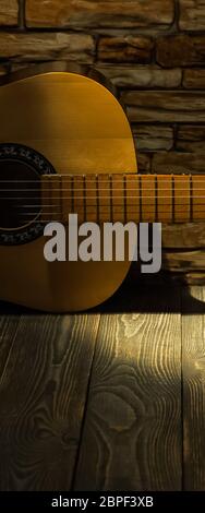 Acoustic guitar lies on the background of a brick wall. Stock Photo