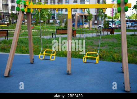 Empty chain swing in playground. Children park with yellow swings. Stock Photo