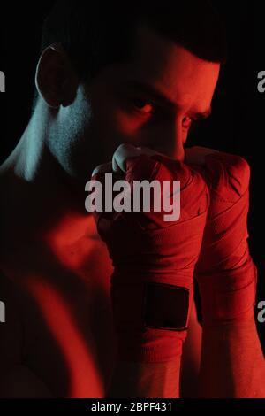Fighter close up portrait before fight, over black background in red light. Determination concept. Stock Photo