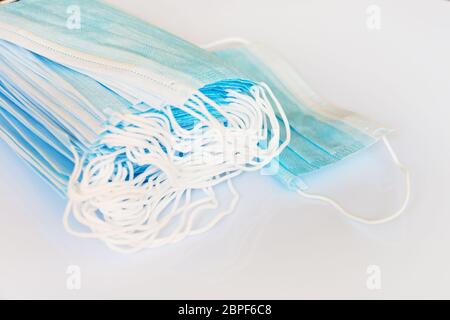 Pile of surgical medical disposable face masks  on panoramic white background with copy space, Covid-19 protection illustration Stock Photo