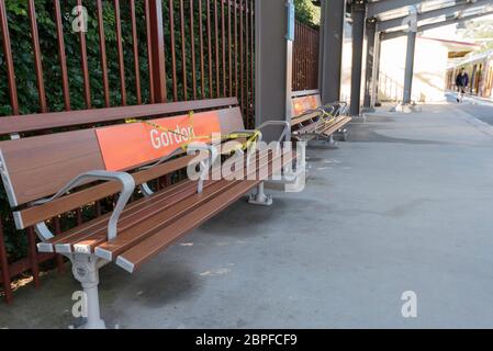 Seats on an almost empty platform of a railway station in Sydney are partly taped off to maintain social distancing during the Covid-19 epidemic Stock Photo