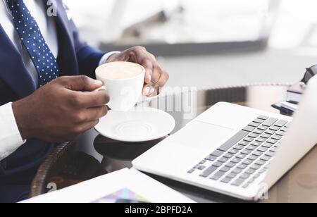 Unrecognizable Businessman Having Coffee Working On Laptop In Cafe, Closeup Stock Photo
