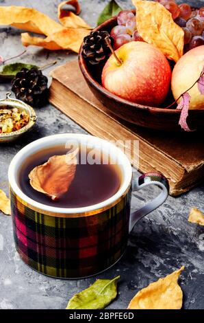 Cup with tea on autumn background of fallen leaves and apples.Autumn still life Stock Photo