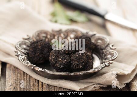 Black truffles on plate  on old wooden table. Stock Photo
