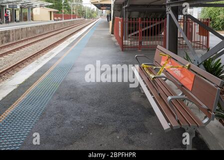 Seats on an almost empty platform of a railway station in Sydney are partly taped off to maintain social distancing during the Covid-19 epidemic Stock Photo