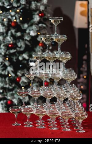 Champagne tower on a red table with Christmas tree in the background Stock Photo