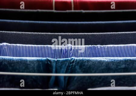 Different types of clothes left hanging to dry on a drying rack Stock Photo
