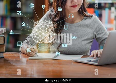 Polygonal brain shape of an artificial intelligence with various icon of smart city Internet of Things Technology over Asian young Student using techn Stock Photo