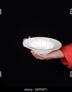 male hand holding empty white ceramic soup plate on black background Stock Photo