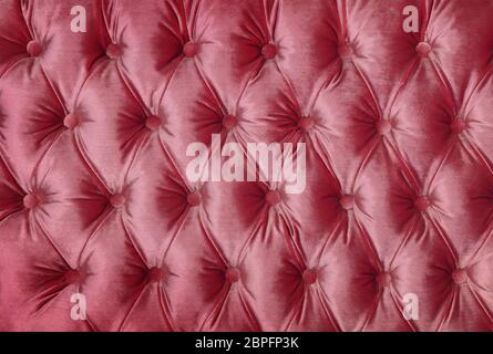 Pastel pink capitone textile background, retro Chesterfield style checkered soft tufted fabric furniture decoration with buttons, close up Stock Photo
