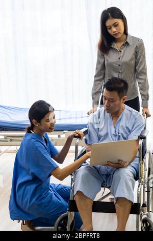 Physical therapist explain treatment method to senior patient and relative using notebook Stock Photo