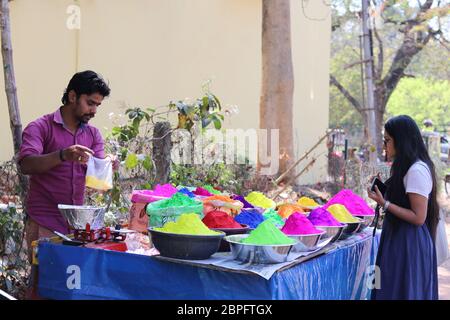 a girl in Bolpur Street Market Stall buying powder dry colours on Holi Festival occasion. Holi is Famous Festival of colours celebrated all Indian Stock Photo
