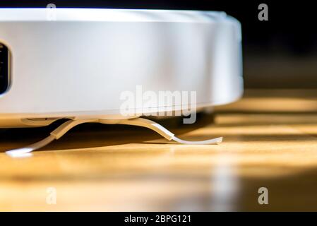 Smart home. Robot vacuum cleaner performs automatic cleaning of the apartment at a certain time. Close up view with selective focus. Stock Photo
