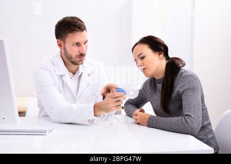 Young Male Doctor Giving Information On Using Oxygen Mask To Woman In Clinic Stock Photo