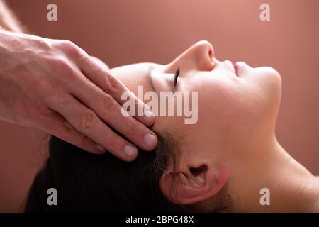 Close-up Of A Therapist Hand Massaging Young Woman's Head Stock Photo