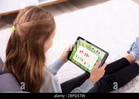 Girl Using Digital Tablet For Solving Math At Home Stock Photo