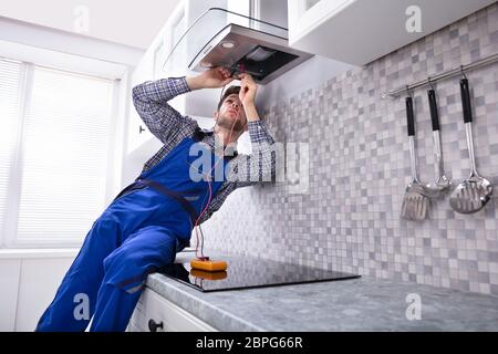 Handyman Checking Kitchen Extractor Filter With Multimeter In Kitchen Stock Photo
