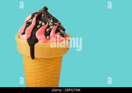Ice cream. Sweet pink ice cream in a waffle cone poured with chocolate on a turquoise background.Beautiful dessert. Stock Photo