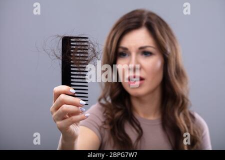 Close-up Of A Worried Woman Holding Comb Suffering From Hairloss Stock Photo