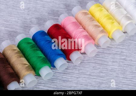 Multi-colored spools of thread on a gray background. Stock Photo