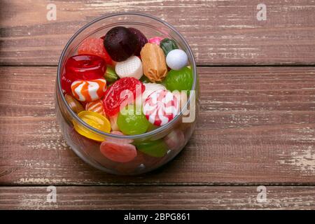 Candies in a jar on a wooden background. Multi-colored caramel. Sweets. Stock Photo
