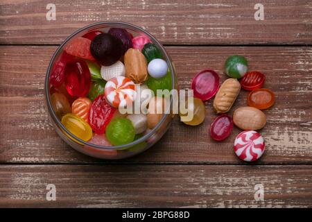Candies in a jar on a wooden background. Multi-colored caramel. Sweets. Stock Photo