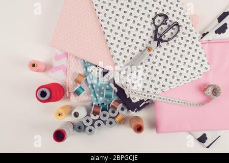 top view of cotton fabric material for tailor or homework, sewing concept with yellow tailor's meter, threads and scissors Stock Photo
