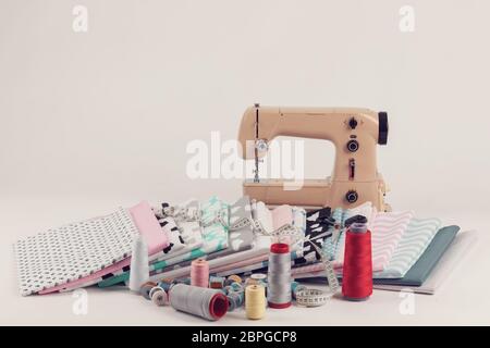 top view of cotton fabric material for tailor or homework, sewing concept with sewing machine, white tailor's meter, threads and scissors Stock Photo