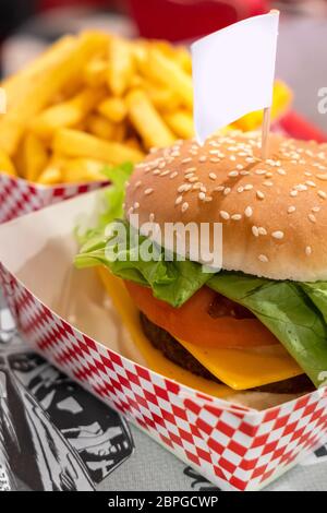 Vegetarian burger, with space for text in empty label (flag) . Vegan meat. On defocused blurry background the fries. Stock Photo