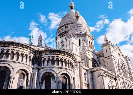 Wide angle shot to Sacre Coeur Basilica in Paris. Wonderful architecture of old French buildings. Clouds in the sky with a bright blue tone. Shot from Stock Photo