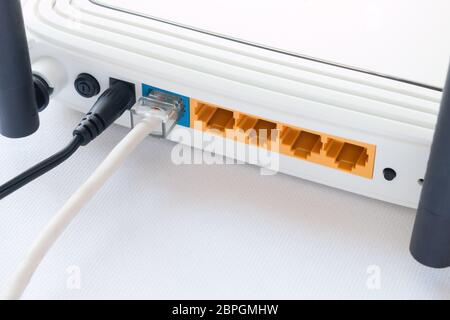 router and the connected internet cable close up on white background Stock Photo