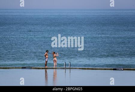 A couple walk around the sea pool during the warm weather in Margate, Kent, after the introduction of measures to bring the country out of lockdown. Stock Photo