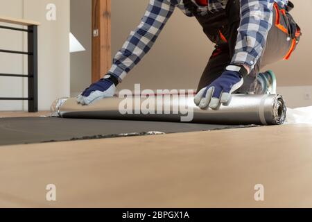 Construction worker installing laminate floor in a new renovated attic. Home improvement concept. Stock Photo