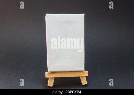Painted canvas stands on an easel. On the screen, a holiday landscape with ocean in the background. Stock Photo