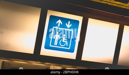blue sign on bright background indicating access to lifts for persons with reduced mobility