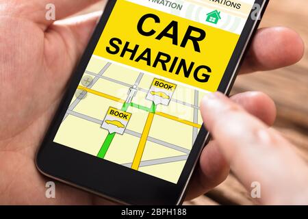 Close-up Of A Person's Hand Using Car Sharing Application On Mobile Phone Stock Photo