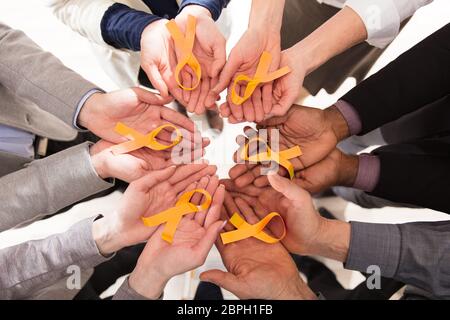Group Of Businesspeople Holding Teal Ribbons To Support Childhood And Bladder Cancer Stock Photo
