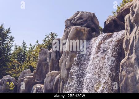 sparkling in sunlight waterfall with blue skies on background and trees Stock Photo