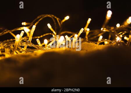 New Year's glowing garland on the snow. Stock Photo