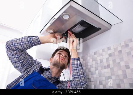 Handyman Checking Kitchen Extractor Filter With Multimeter In Kitchen Stock Photo