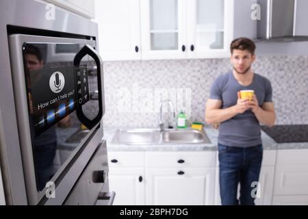 Close-up Of An Oven With Voice Recognition Function Near Man Standing In Kitchen Stock Photo