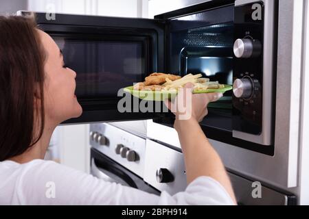 https://l450v.alamy.com/450v/2bph914/close-up-of-a-young-woman-heating-fried-food-in-microwave-oven-2bph914.jpg