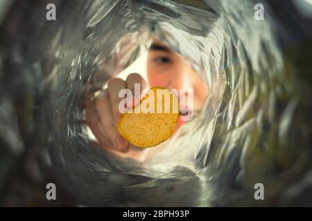 teenager takes out potato chips from a pack, view from a pack on a child Stock Photo