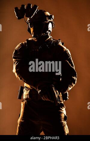 Anti terrorist squad fighter, army elite forces soldier in mask, with night vision device and tactical radio headset on helmet, armed service pistol s Stock Photo